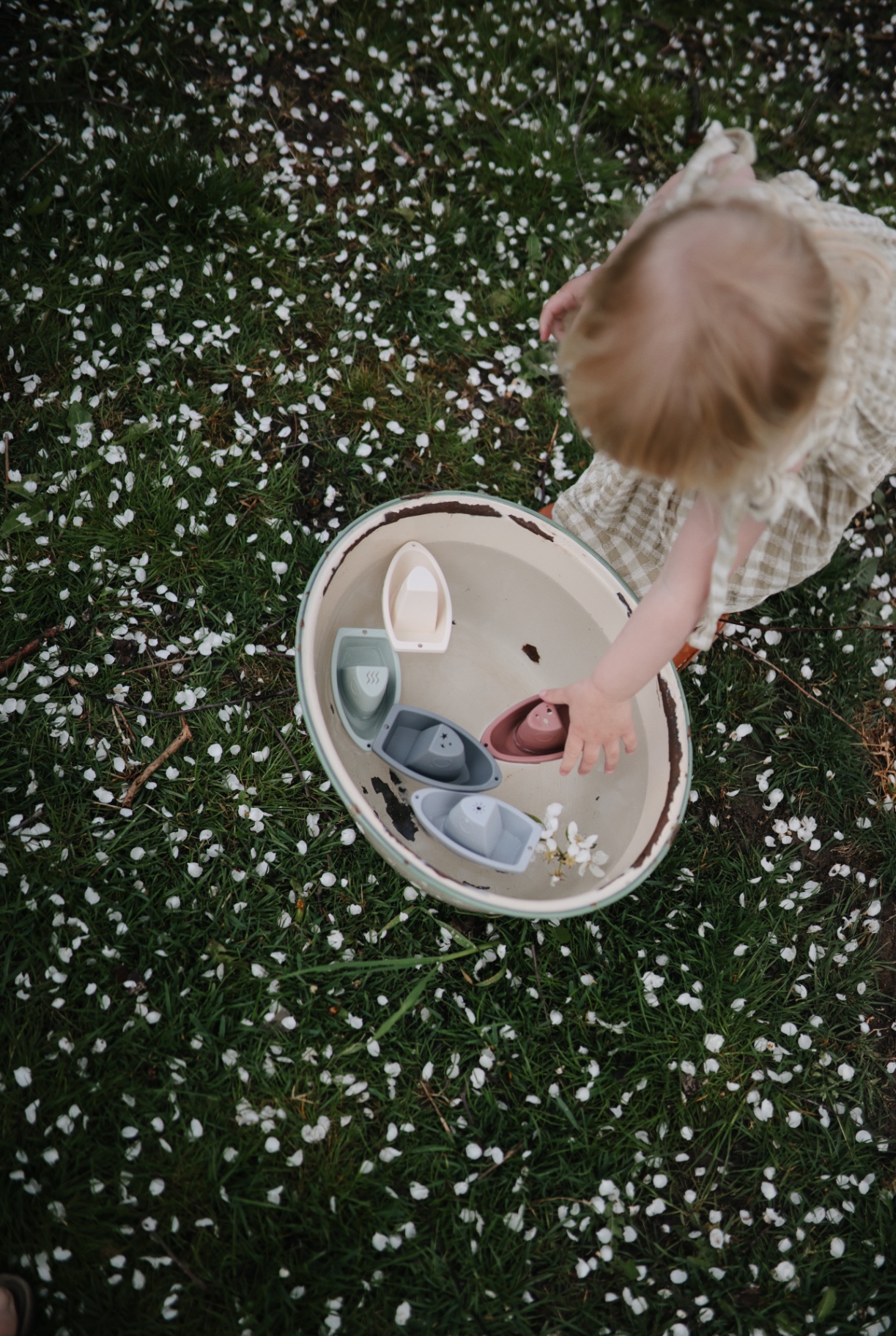 Girl playing with silicone boats in the garden