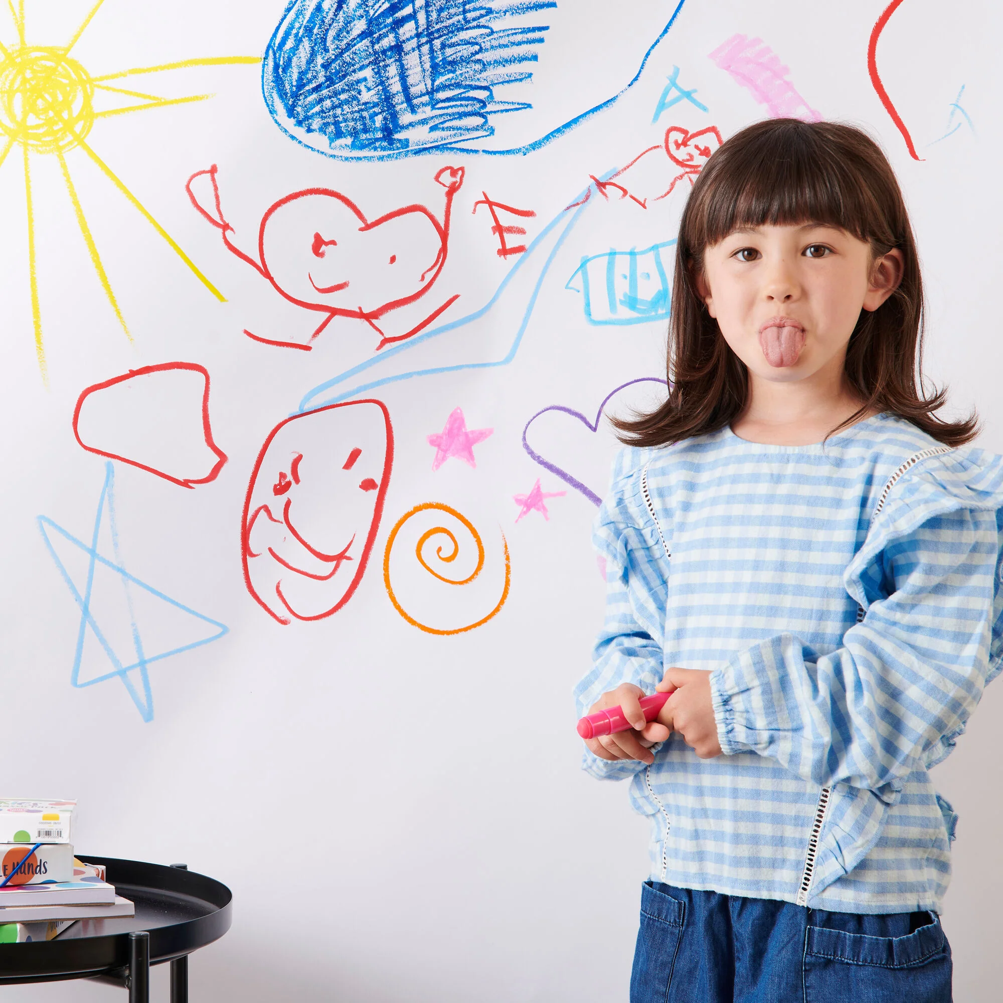 Girl drawing with colorful crayons on a wall