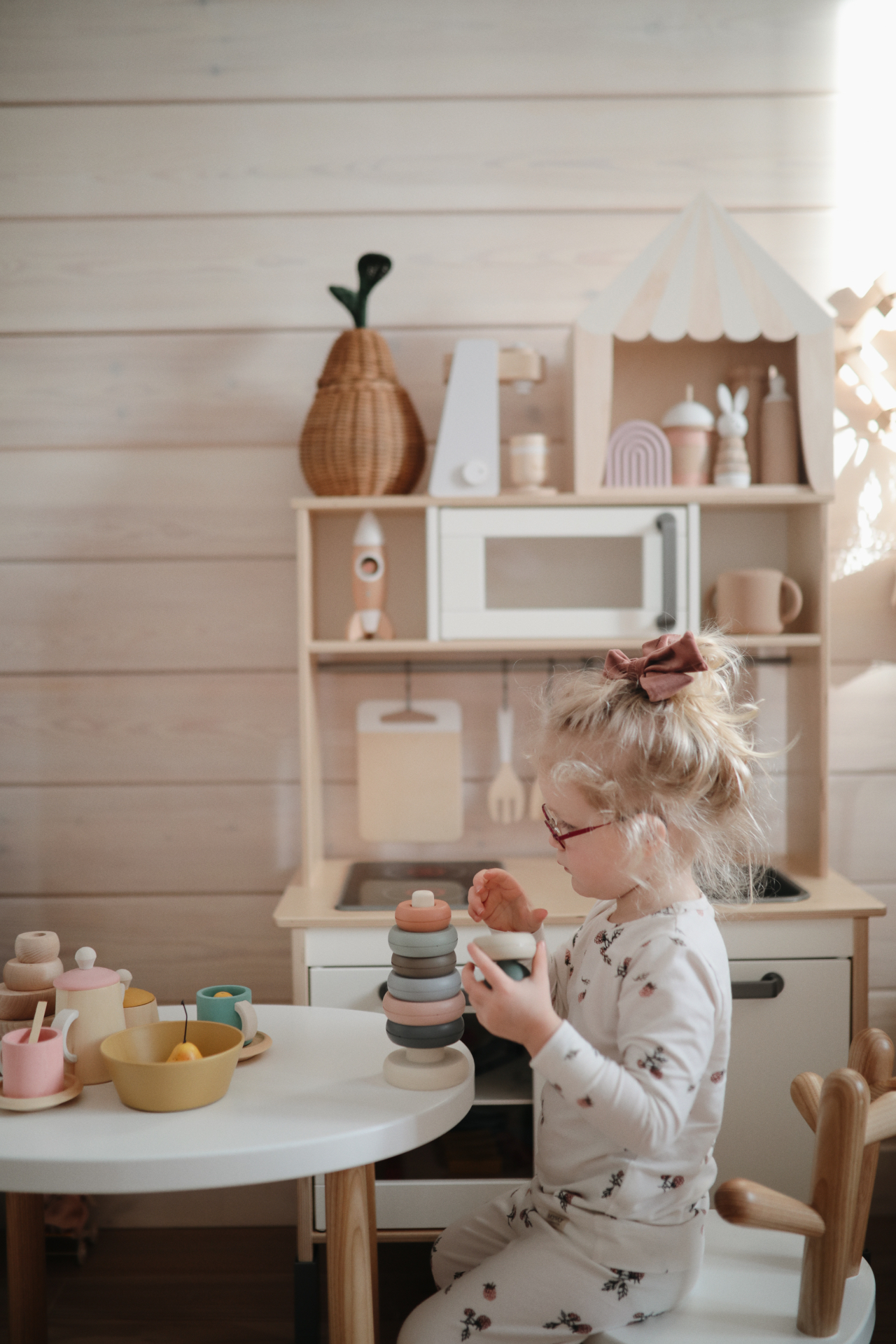 Girl playing with wooden stacking rings and a tea set